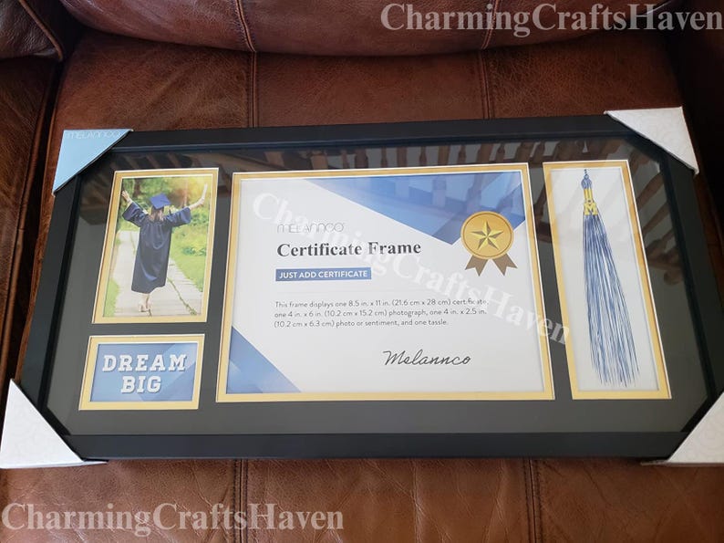 May include: Black certificate frame with gold accents, holding a graduation photo, certificate, and tassel. The frame includes the text "DREAM BIG" and "Certificate Frame". The frame displays one 8.5 in x 11 in (21.6 cm x 28 cm) certificate.
