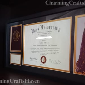 May include: A framed diploma from Park University, with a Bachelor of Science degree in Criminal Justice Administration. The frame also includes a tassel and a small document, all with gold accents.
