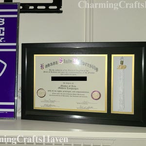 May include: A framed diploma from Kansas State University, with a black frame and gold accents. The diploma is for a Master of Arts in Modern Languages. A tassel with a 2019 charm is displayed next to the diploma.