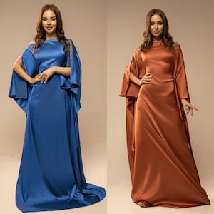 May include: Two women wearing long, flowing gowns. The woman on the left is wearing a blue gown with a wide, flowing sleeve. The woman on the right is wearing a rust-coloured gown with a wide, flowing sleeve.