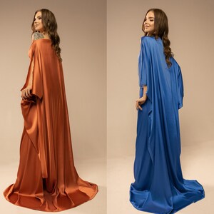 May include: Two women wearing long, flowing gowns. One gown is a deep orange colour, and the other is a bright blue.