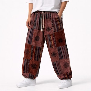 Könnte beinhalten: Braune Patchworkhose mit Kordelzug und elastischen Knöcheln. Die Hose hat verschiedene Blumen- und geometrische Muster in Braun-, Rot- und Orangetönen. Hergestellt aus einem weichen, bequemen Material.