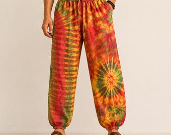 May include: Tie-dye pants in shades of red, yellow, and green. The pants have a drawstring waist and elastic cuffs at the ankles. The fabric features a spiral tie-dye pattern on the legs. The pants are part of a casual clothing collection.