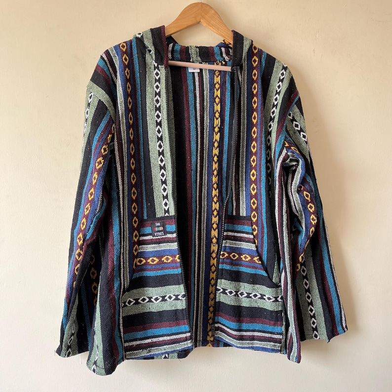 May include: A hooded jacket with a colorful striped pattern. The jacket features vertical stripes in black, blue, green, and red, with decorative diamond and zigzag patterns. It has two front pockets and a small patch with text.
