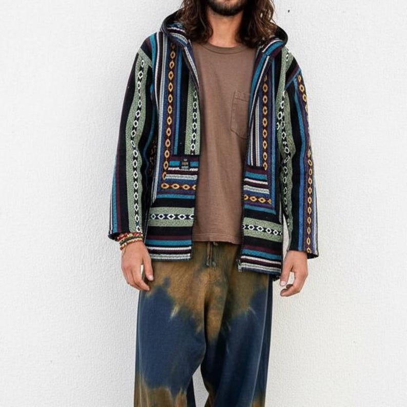 May include: A hooded jacket with a colorful, striped pattern in shades of blue, green, and black. The jacket has a front pocket and a zipper closure. The person is also wearing a brown t-shirt and tie-dye pants.