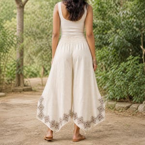 May include: Cream-colored wide-leg pants with a geometric pattern at the hem. The pants have a high waist and are paired with a matching tank top. The outfit is casual and suitable for warm weather.