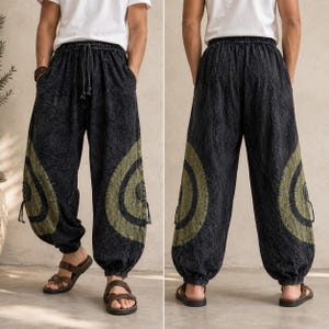 May include: Black harem pants with olive green circular designs on the sides. The pants have a drawstring waist and pockets. The fabric has a textured appearance. The pants are shown from the front and back.