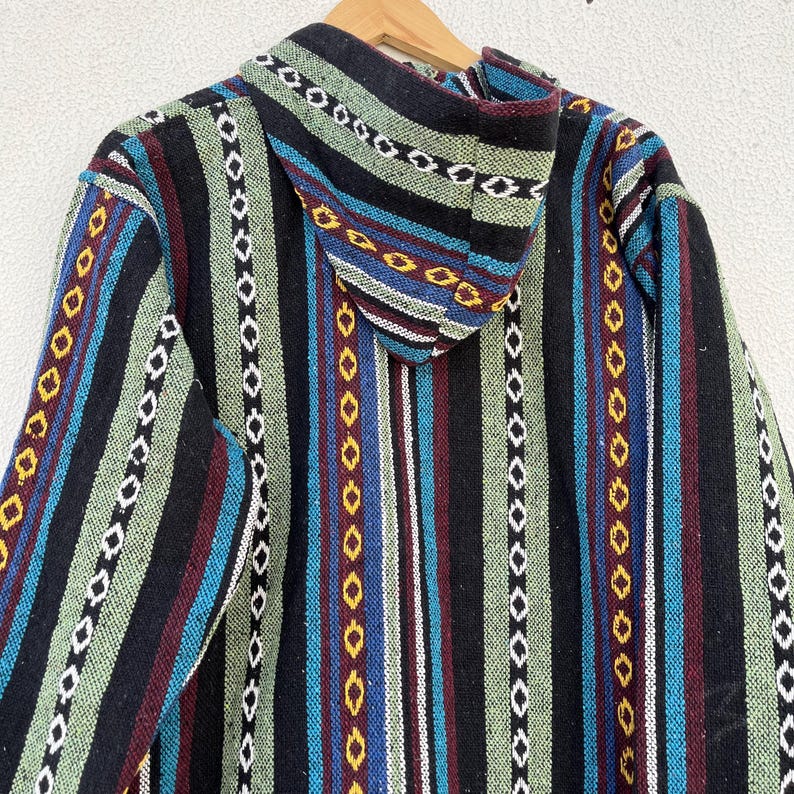May include: A hooded jacket with a colorful striped pattern. The jacket features vertical stripes in black, green, blue, red, and white, with decorative stitching. The hood is also striped. The jacket is hanging on a wooden hanger.