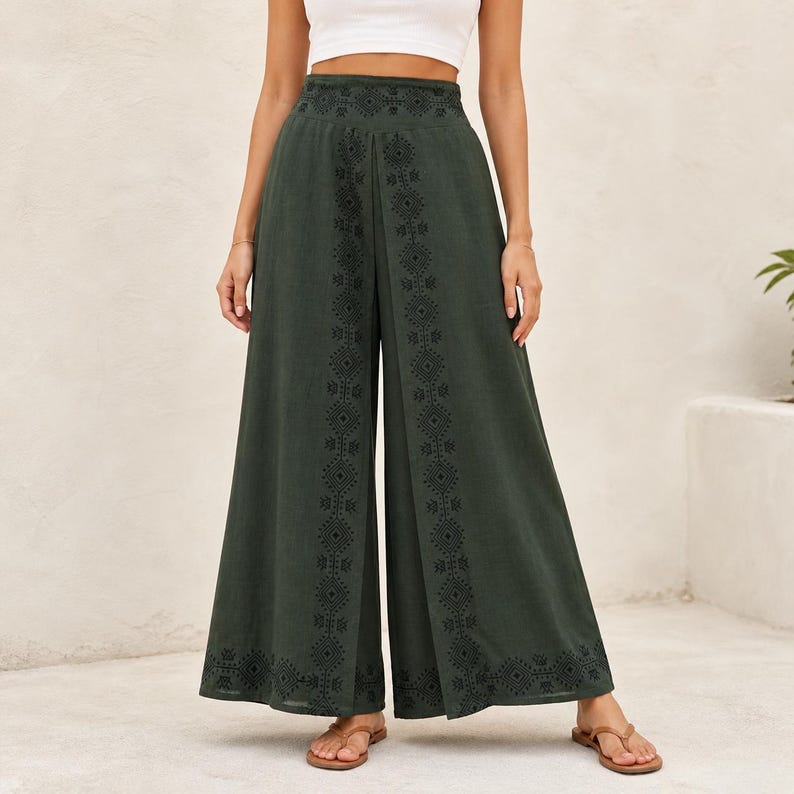 May include: Dark green palazzo pants with embroidered geometric patterns along the sides and waistband. The wide-leg pants are made of a flowing fabric and are worn with sandals. The pants have a high waist and a split front.
