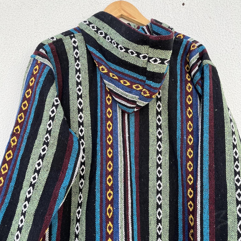 May include: A hooded jacket with a colorful striped pattern. The jacket features vertical stripes in black, green, blue, and maroon, with decorative stitching. The hood is also patterned. The jacket is hanging on a wooden hanger.