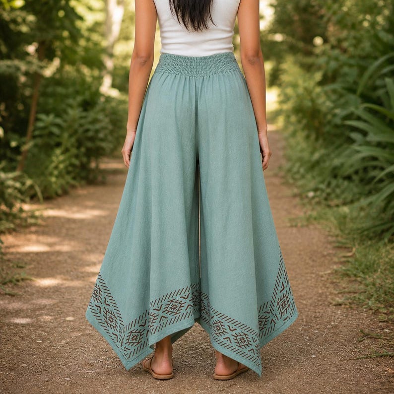 May include: Wide-leg, light teal pants with an elastic waistband and a geometric pattern near the hem. The pants are worn with a white top. The pants are made of a soft, flowing fabric, perfect for warm weather.