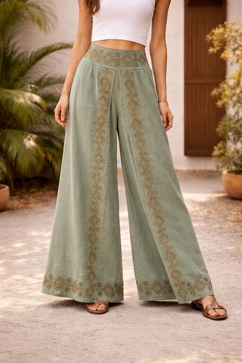 May include: Sage green palazzo pants with intricate embroidered detailing in a geometric pattern. The wide-leg pants feature a high waist and are made of a lightweight fabric. The pants are a stylish choice for casual wear.