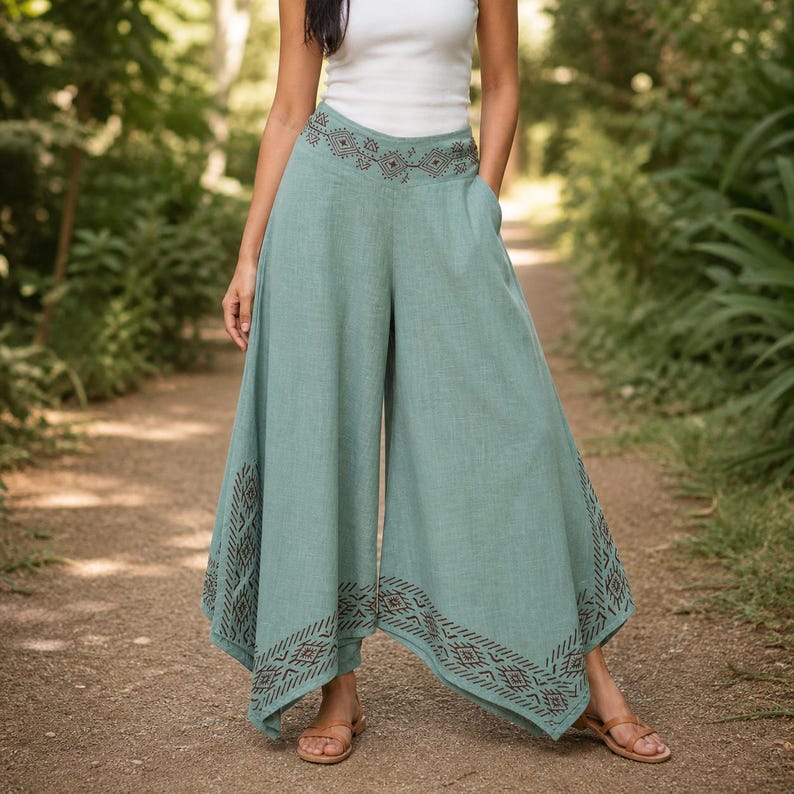 May include: Light teal palazzo pants with a wide leg design. The pants feature a decorative geometric pattern in a darker shade of teal along the pockets and hem. The pants are made of a lightweight fabric.