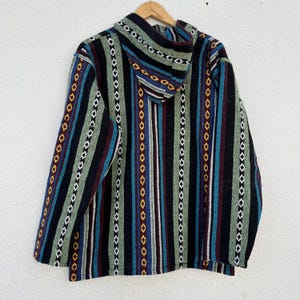 May include: A hooded jacket with a colorful striped pattern. The jacket features vertical stripes in black, green, blue, red, and yellow. The hood is visible at the top, and the jacket is hanging on a wooden hanger.