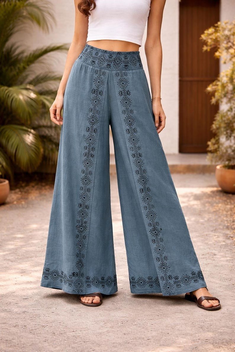 May include: Wide-leg, blue pants with intricate black geometric patterns along the sides and waistband. The pants are made of a soft fabric and are worn with sandals. The pants are a stylish addition to any wardrobe.