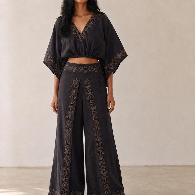 May include: A black two-piece outfit comprising a cropped top and wide-leg trousers. The top has a V-neck and short, kimono-style sleeves. Both garments are embellished with detailed gold embroidery along the borders and seams, forming a coordinated and stylish set.
harem pants, yoga pants women, hippie pants, loose fit trousers, Gifts for Her, wide leg pants, travel outfits, boho coord set, two piece set, festival outfits, v-neck dress, flowy pants set, Party Wear Dress