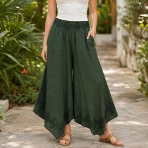May include: Dark green palazzo pants with a geometric pattern at the waist and hem. The wide-leg pants have pockets and are paired with brown sandals. The model is wearing a white tank top.