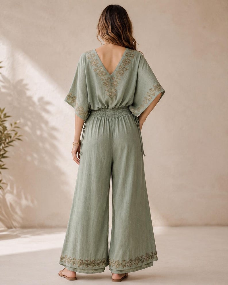 May include: Sage green jumpsuit with a V-neckline and wide-leg pants. The top features embroidered detailing along the neckline and sleeves. The waist is elasticized. The bottom of the pants also has embroidered detailing.
