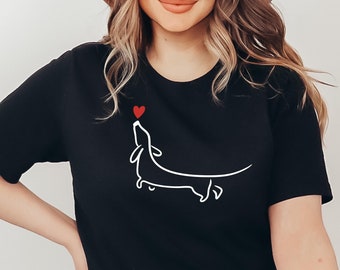 May include: Black t-shirt with a white outline of a dachshund looking up at a red heart.