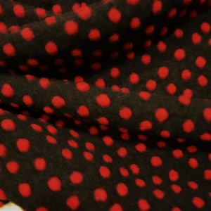 Könnte beinhalten: Schwarzer Stoff mit roten Punkten. Der Stoff ist weich und flauschig.