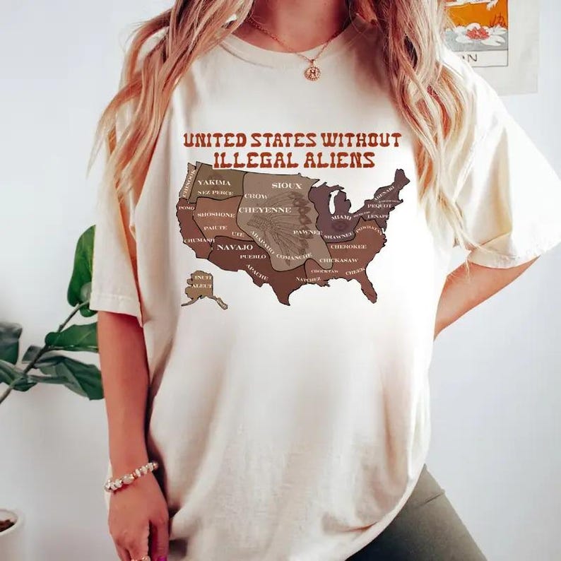 May include: Cream-colored t-shirt featuring a map of the United States with various tribal names and the text "UNITED STATES WITHOUT ILLEGAL ALIENS" in brown. The shirt is a casual wear item.