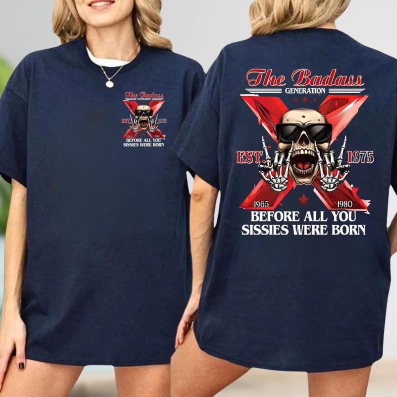 Może przedstawiać: Granatowy t-shirt z grafiką czaszki w okularach przeciwsłonecznych i szkieletowymi dłońmi wykonującymi gest rockowy na tle czerwonego X. Tekst głosi The Badass Generation, Est 1975, 1965, 1980 oraz Before All You Sissies Were Born.