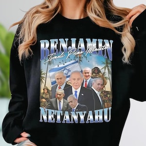 May include: Black sweatshirt featuring a graphic of Benjamin Netanyahu, the Israeli Prime Minister, with the Israeli flag and palm trees. The text "BENJAMIN Israeli Prime Minister NETANYAHU" is displayed in a stylized font.