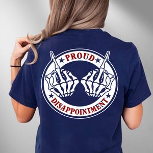 May include: Navy blue t-shirt with a white graphic of two skeleton hands giving the middle finger. The graphic is within a white circle, with the words "PROUD" and "DISAPPOINTMENT" in red and white.