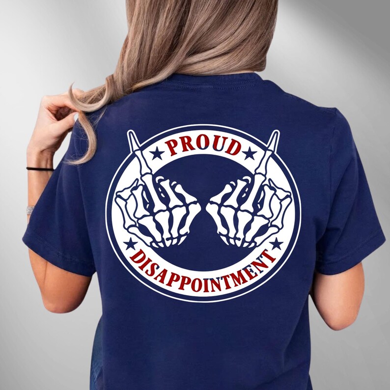 May include: Navy blue t-shirt with a white graphic of two skeleton hands giving the middle finger. The graphic is within a white circle, with the words "PROUD" and "DISAPPOINTMENT" in red and white.