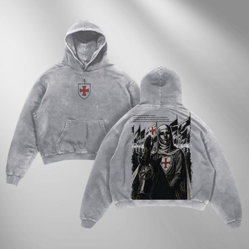 May include: Gray hoodie with a front pocket and hood. The front features a shield with a red cross. The back displays a detailed illustration of a knight on horseback, with text and flags. The hoodie has a vintage, washed appearance.