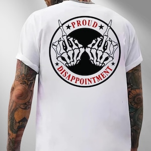 May include: White t-shirt featuring a black and red graphic on the back. The graphic is a circle with the words "PROUD" and "DISAPPOINTMENT" around two skeleton hands giving the middle finger.