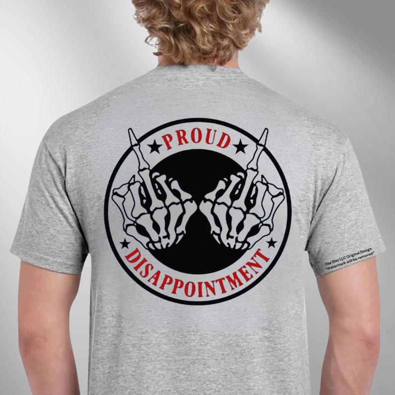 May include: A light grey t-shirt with a black and red graphic. The graphic features a black circle with the words "PROUD" and "DISAPPOINTMENT" and two skeleton hand gestures. The t-shirt is a crew neck style.