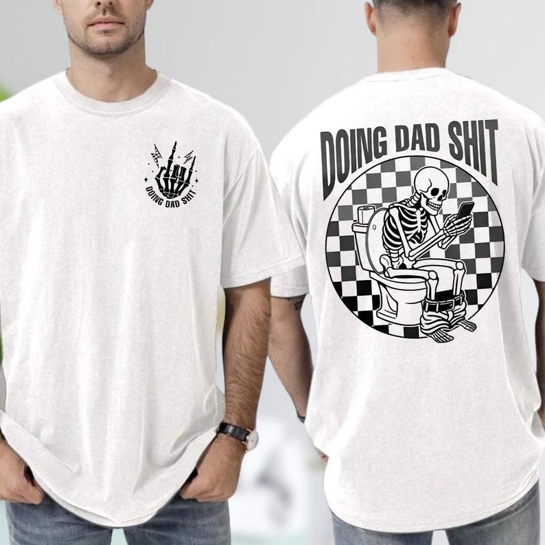 May include: White t-shirt with black graphic designs. The front features a skeleton hand with the text "DOING DAD SHIT". The back displays a skeleton on a toilet, using a phone, with the same text in a checkered circle.