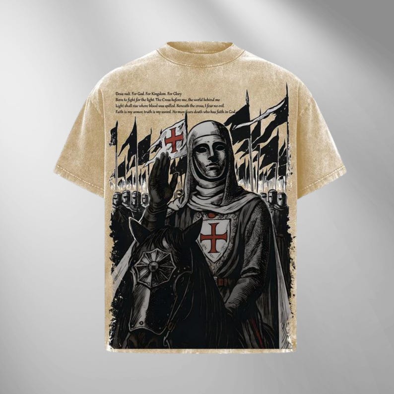 May include: Beige t-shirt featuring a graphic of a knight on horseback, with a cross emblem on the shield and flags in the background. The shirt has text at the top. The design is vintage-inspired.
