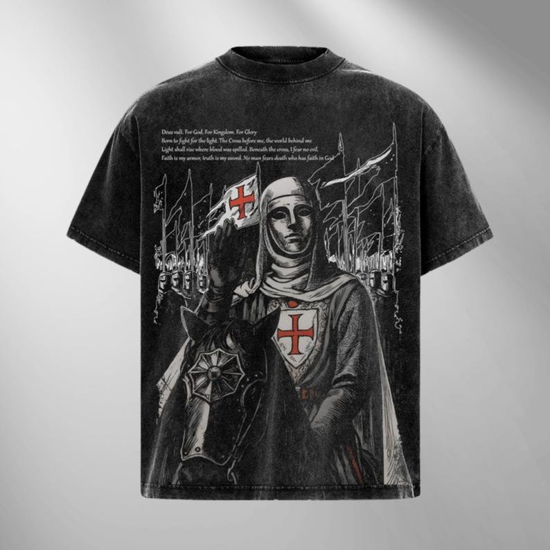May include: Black graphic t-shirt featuring a medieval knight on horseback holding a flag with a red cross. The design includes text and a distressed, vintage aesthetic. The shirt has a crew neck and short sleeves.