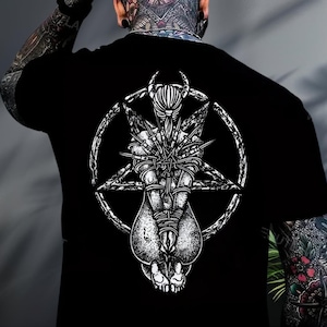 May include: Black t-shirt featuring a detailed white graphic on the back. The design includes a pentagram, a central figure bound with thorns, and other symbolic elements. The shirt's design is intricate and bold.