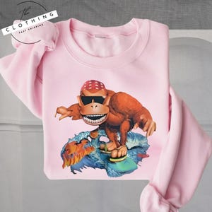 a pink shirt with a picture of a dinosaur on it