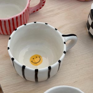 Taza de cerámica blanca con rayas negras pintadas a mano - Taza de cerámica única hecha a mano - Bonita taza de café de arcilla estética con una sonrisa en el interior