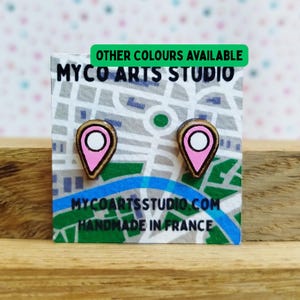 May include: Wooden stud earrings in the shape of pink location markers with white centers. The earrings are displayed on a card with a map design and the text "MYCO ARTS STUDIO". The green text on the card says "OTHER COLORS AVAILABLE".