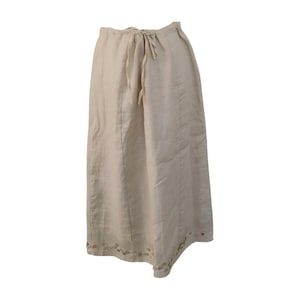 May include: Beige linen trousers with a drawstring waist. The wide-leg trousers have a relaxed fit and decorative cut-out details near the hem. The trousers are made of a lightweight fabric, suitable for warmer weather.