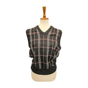 May include: A gray, sleeveless V-neck sweater vest with a plaid pattern in white and red. The vest is displayed on a mannequin against a white background. The sweater vest is a classic style.