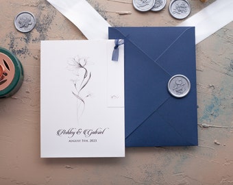 Wedding invites feature guest names, script, ribbon, envelope, wax seal for minimalist touch