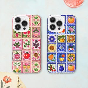 Può includere: Due custodie per iPhone con un design a patchwork colorato. La custodia a sinistra ha uno sfondo rosa con fiori e frutti rossi, bianchi e verdi. La custodia a destra ha uno sfondo blu con fiori e frutti gialli, rossi e bianchi.
