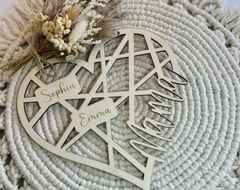 Könnte beinhalten: Ein herzförmiges Schild aus Holz mit geometrischem Design. Die Namen "Sophia", "Emma" und "Mama" sind auf dem Schild eingraviert.