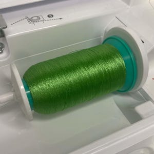 Sakura 40wt 1000m polyester thread spool loaded into a computerized embroidery machine holder