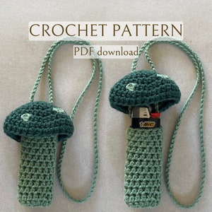 May include: Crochet pattern PDF download for a green mushroom-shaped lighter holder with a white string.