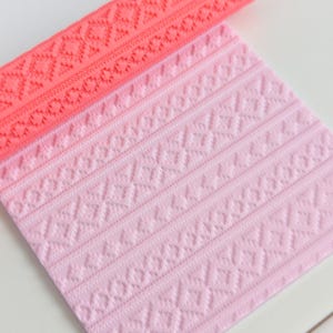 May include: A rolled coral silicone mould and a flat, light pink silicone mould. Both moulds feature a repeating geometric pattern of diamonds and lines, suitable for creating textured designs on craft projects.