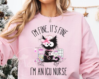May include: Light pink sweatshirt featuring a black cat wearing a nurse's cap and bow. The cat is surrounded by medical supplies. Text on the sweatshirt reads "I'M FINE, IT'S FINE, I'M AN ICU NURSE."