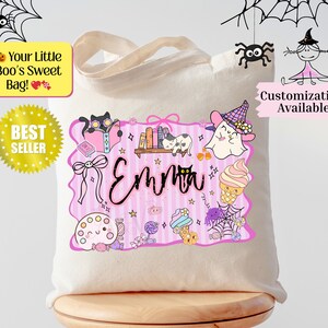 Peut inclure: Un sac fourre-tout en toile beige avec un motif sur le th&egrave;me d'Halloween. Le motif comprend un cadre rose avec le nom "Emma", ainsi que des illustrations de chat, fant&ocirc;me, bonbons et araign&eacute;es. Le texte sur le sac indique "Your Little Boo's Sweet Bag!" et "Best Seller".