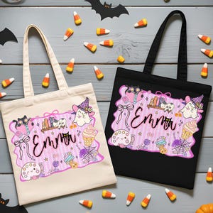 Peut inclure: Deux sacs fourre-tout, un cr&egrave;me et un noir, avec un motif sur le th&egrave;me d'Halloween. Le motif comprend un cadre rose avec le nom "Emma", des fant&ocirc;mes, des chats, des livres, des cornets de cr&egrave;me glac&eacute;e et d'autres illustrations mignonnes. Des bonbons en forme de ma&iuml;s sont &eacute;parpill&eacute;s.